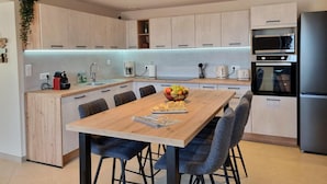 Una cocina moderna con una isla central, electrodomésticos integrados y una zona de comedor con sillas.
