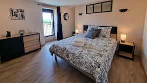 Un dormitorio con cama, mesitas de noche, cómoda y ventana con vistas.