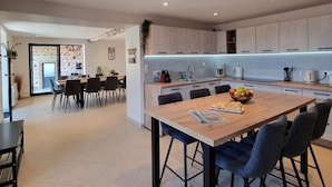 Cocina moderna con una isla central, comedor con sillas y una encimera visible.