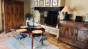 A rustic dining area with a wooden table, woven placemats, and a fireplace.