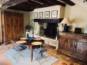 A rustic dining area with a wooden table, woven placemats, and a fireplace.