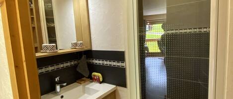 A bathroom with a sink, mirror, and a shower area.
