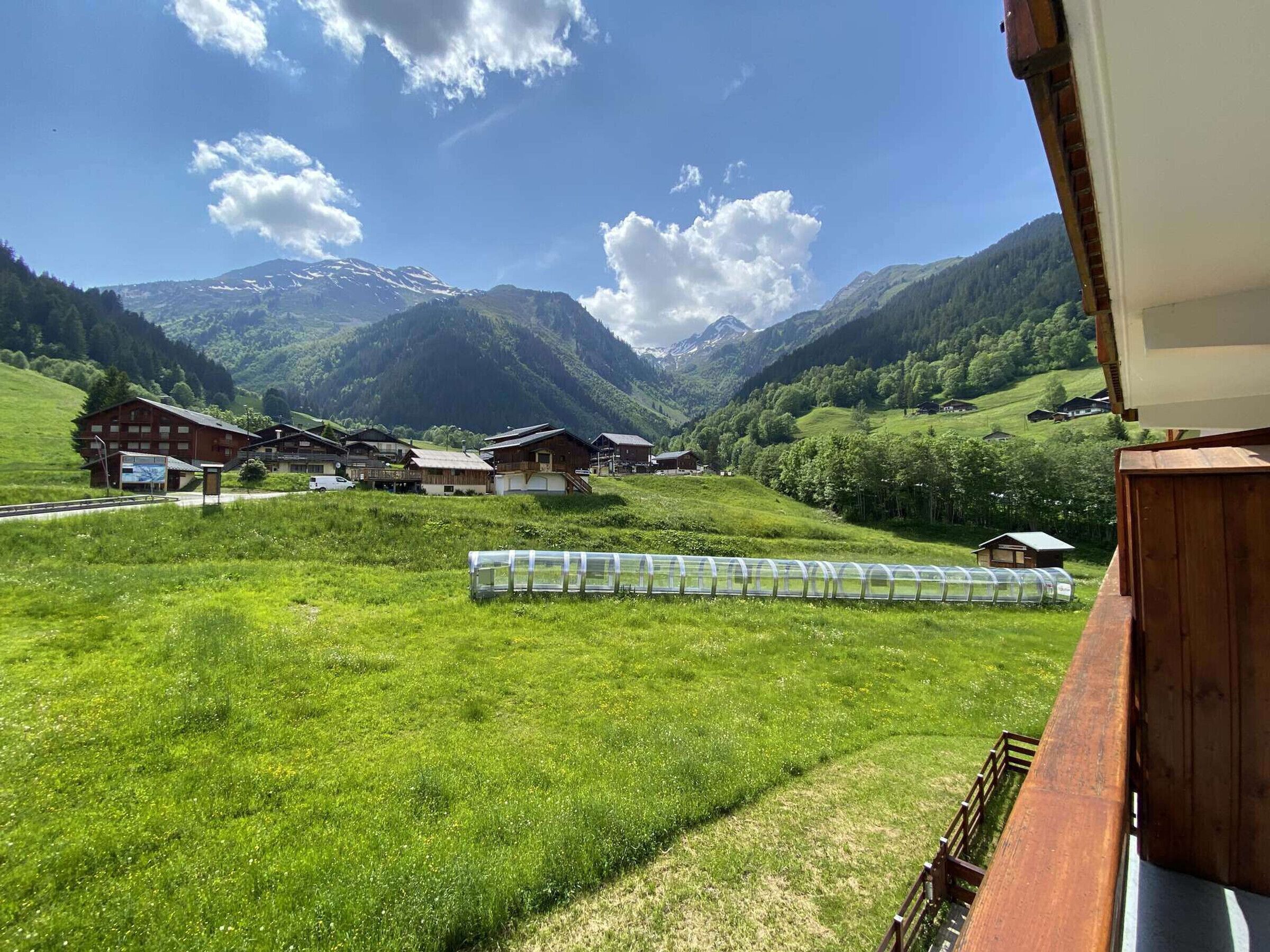 A mountain village with traditional wooden houses, a clear sky, and a view of snow-capped mountains.