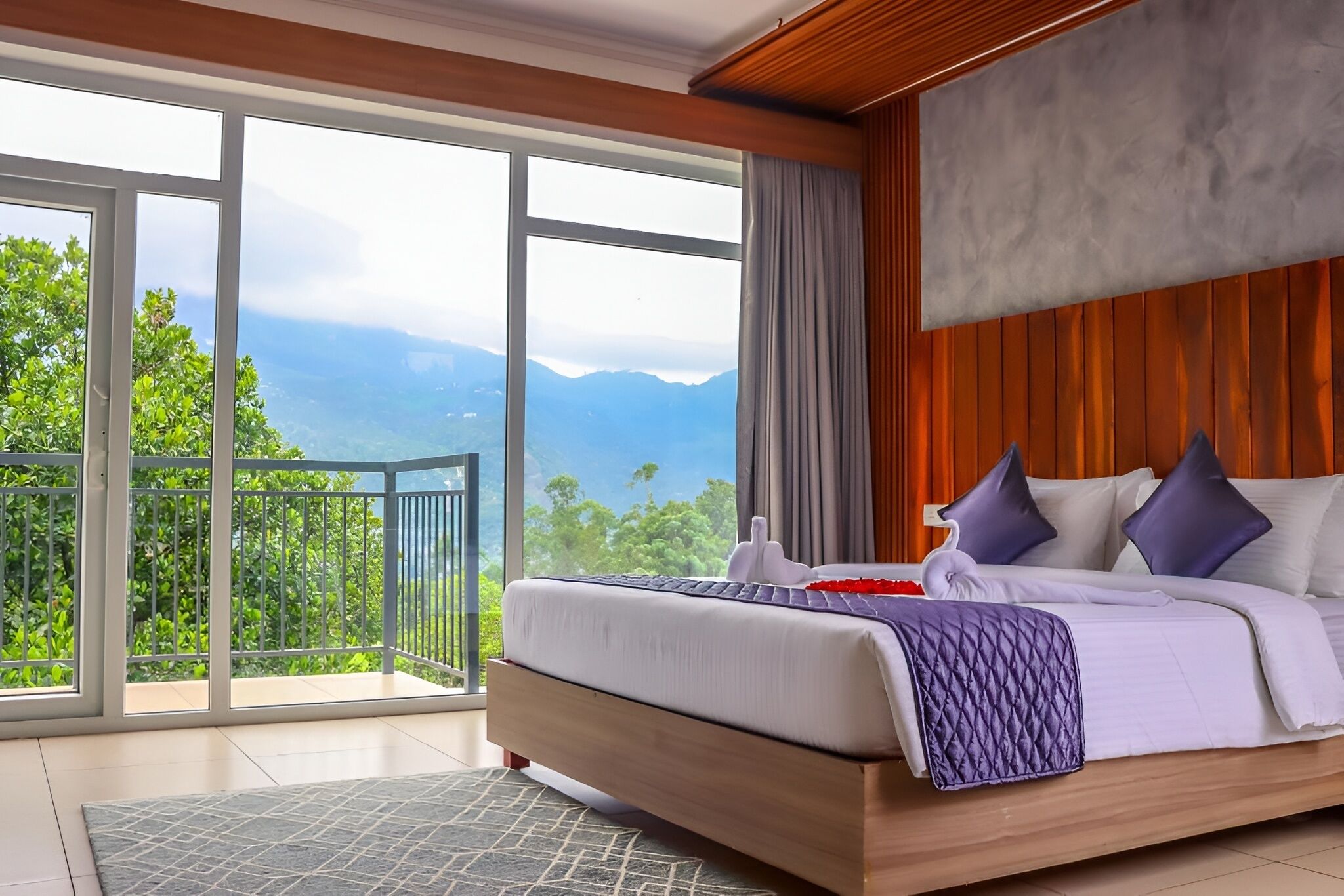 Un dormitorio con una cama grande, vistas a las montañas y un balcón con barandilla.