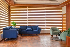 Un salon moderne avec un canapé bleu, un fauteuil vert et une plante en pot.