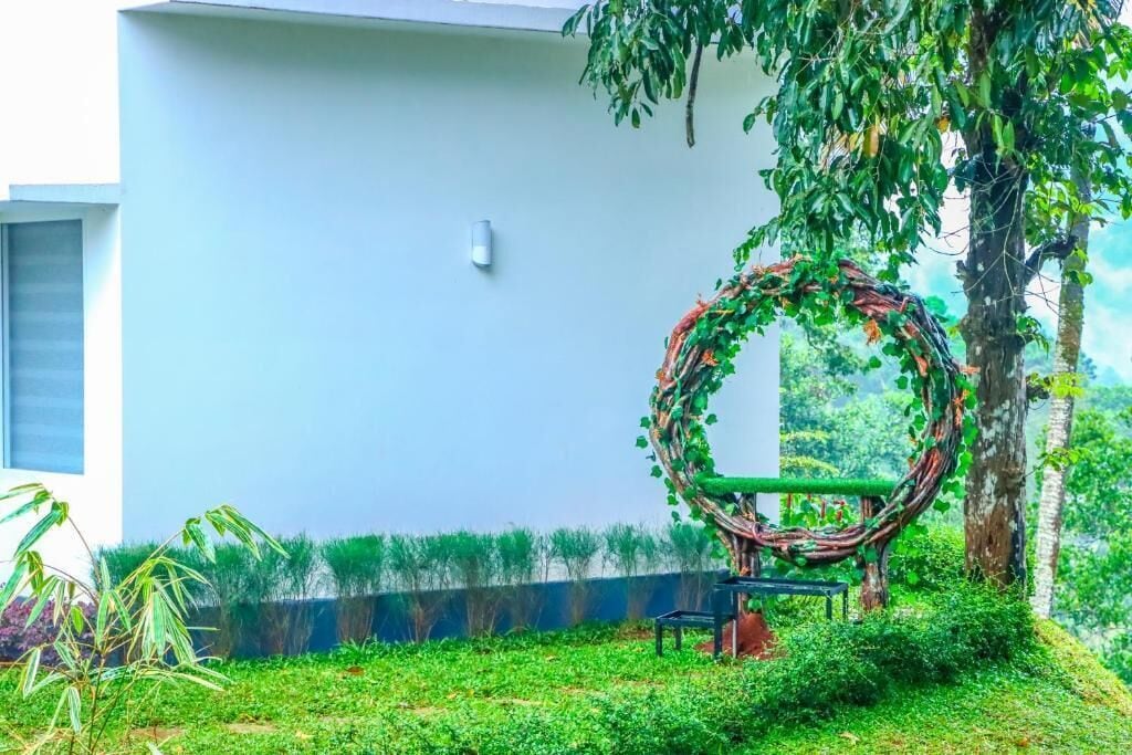 A modern building with a white exterior, a circular garden feature, and a hammock.