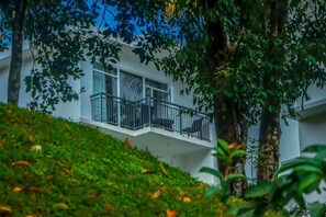 Un edificio moderno con balcón, rodeado de exuberante vegetación.