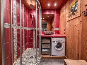 Ein kleines Badezimmer mit Dusche, einer Waschmaschine und einem Waschbecken mit dekorativer Schale.
