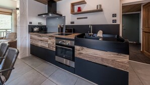 Een moderne keuken met een centraal eiland, een ingebouwde oven en een houten plafond.