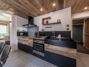 Eine moderne Küche mit Kochinsel, Einbauofen und Holzboden.