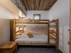Ein Schlafraum mit Etagenbetten, einer Holzbalkendecke und einem kleinen Nachttisch.