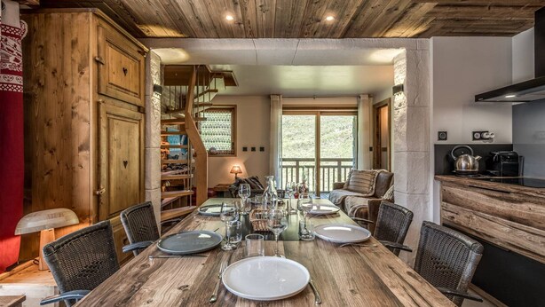 Een eethoek met een houten tafel voor vier personen, omringd door rieten stoelen.