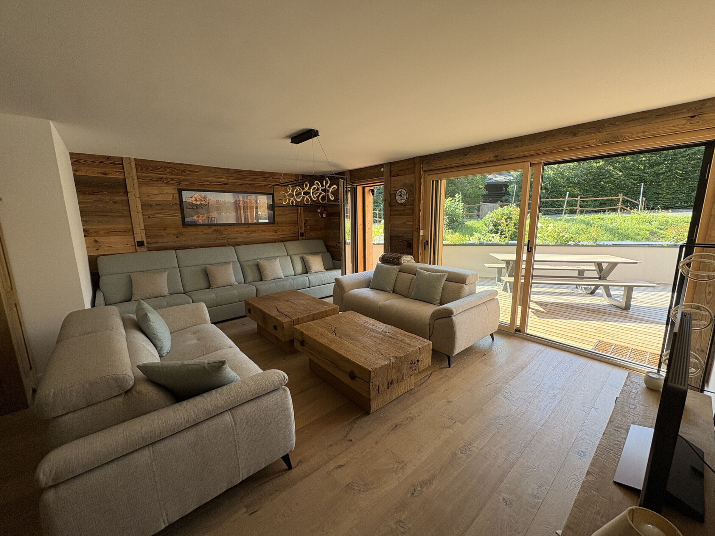 A spacious living area with a sofa set, coffee table, and a sliding glass door leading to an outdoor patio.
