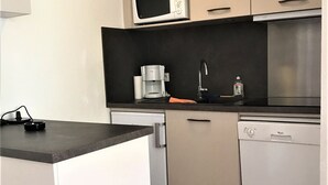 Eine kleine Küche mit Mikrowelle, Kaffeemaschine und Geschirrspüler.
