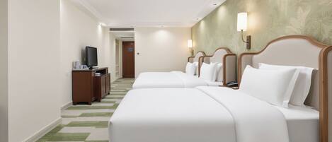 Ein Hotelzimmer mit zwei Betten, einem Schreibtisch mit Computer und einem Fernseher.