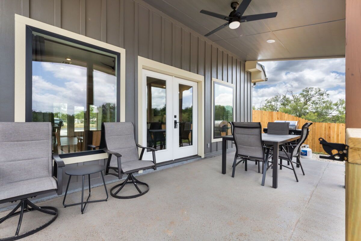 An outdoor patio with seating and a ceiling fan.
