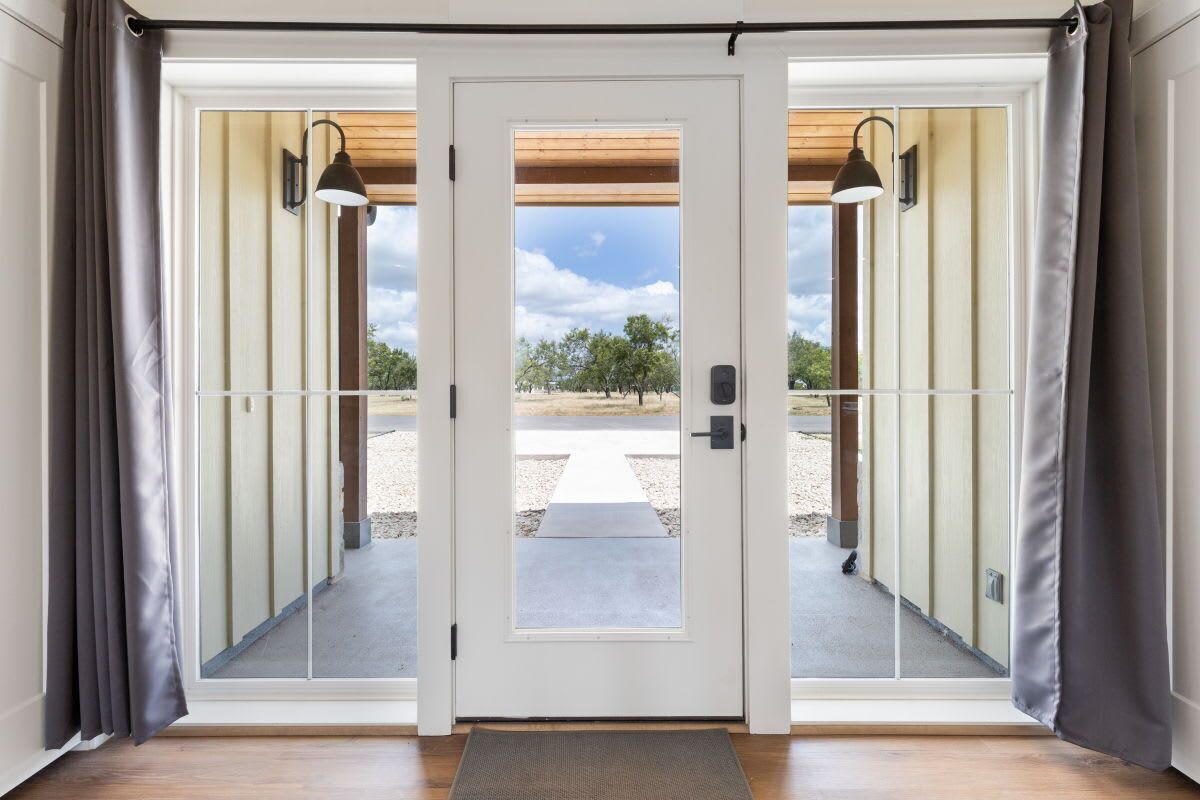 A double door leading to an outdoor area with a view of trees and a clear sky.