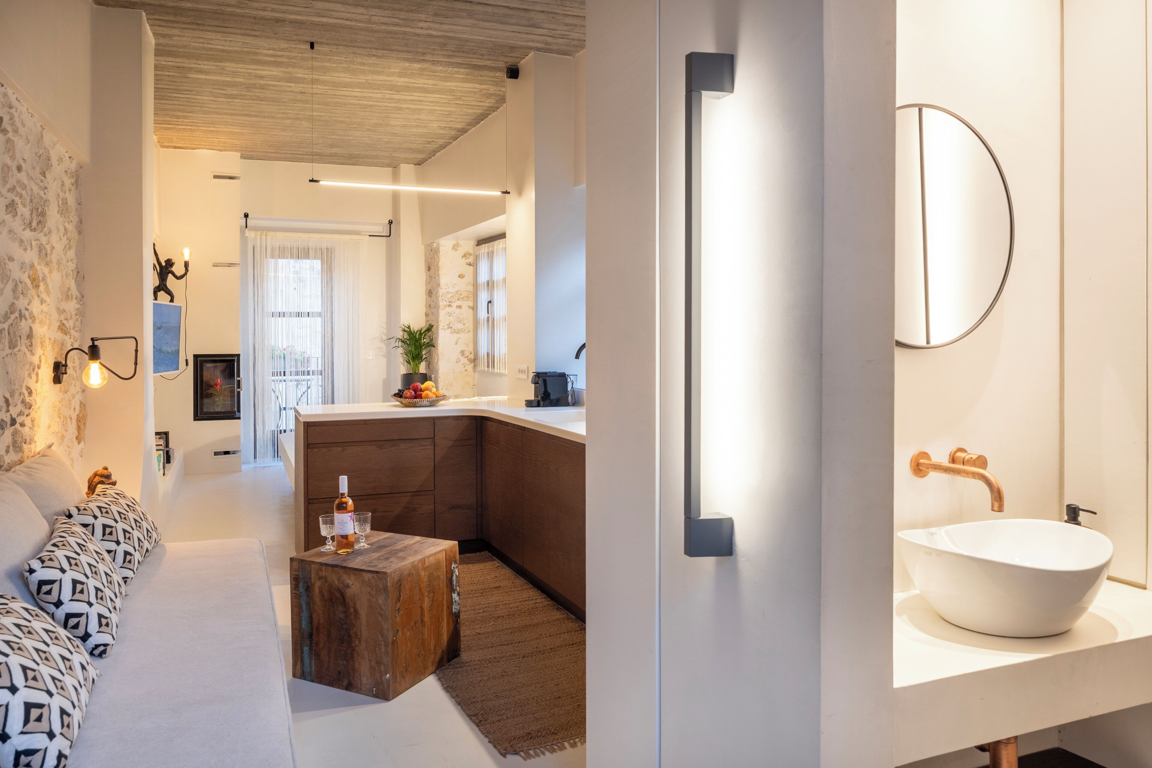 A modern interior with a kitchen, dining area, and a bathroom with a large mirror and white sink.