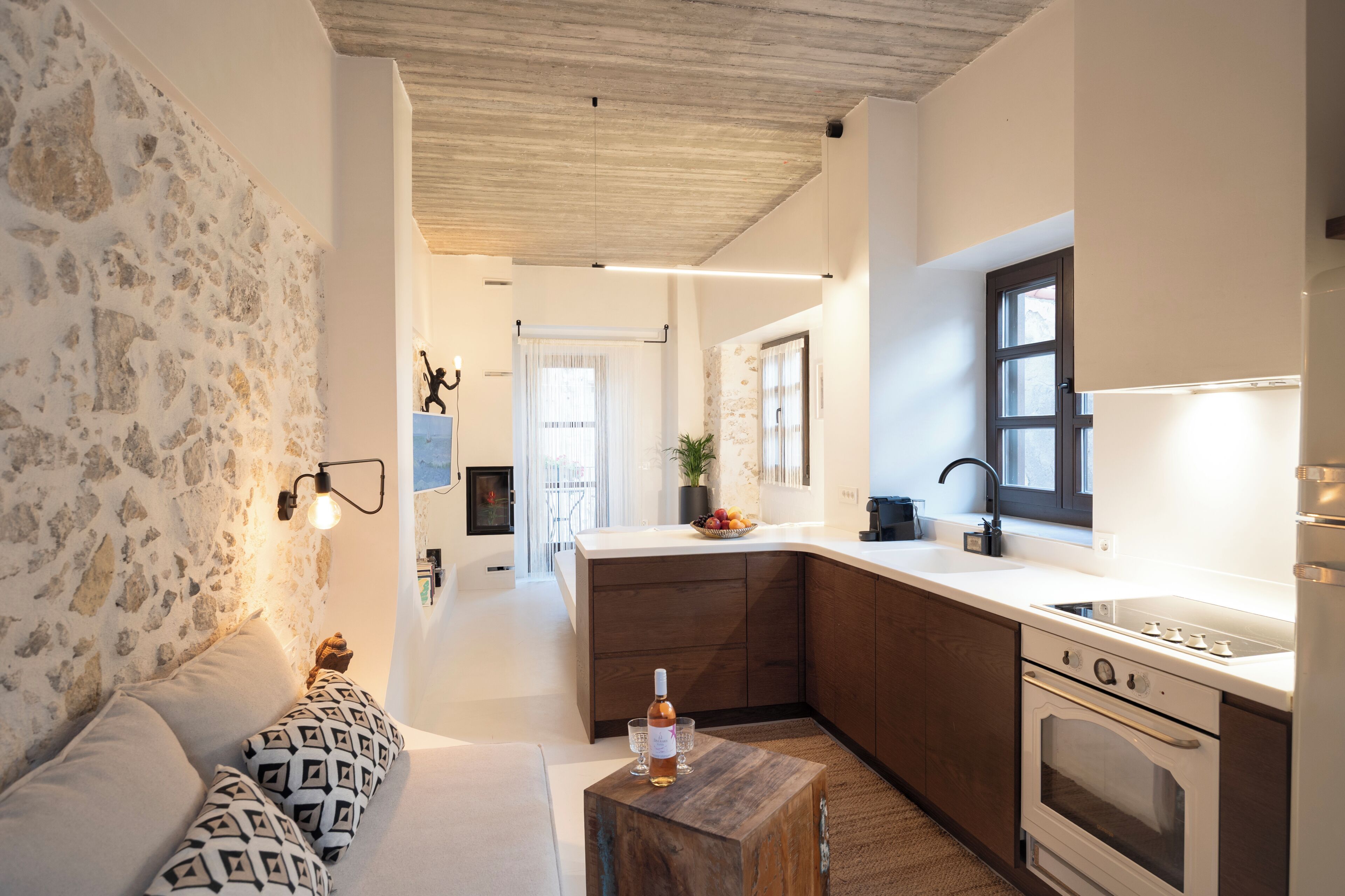 A modern kitchen with a stone wall, wooden cabinets, and a built-in oven.