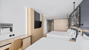 Een hotelkamer met een bureau, twee bedden, een televisie en een schilderij aan de muur.