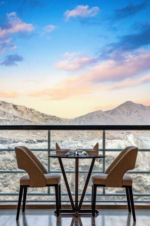 A dining table with two chairs, set against a backdrop of a mountainous landscape and a clear sky. - Radisson Hotel Makkah Thakher City (Makkah)