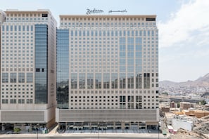 Um edifício moderno de hotel com uma fachada de vidro refletora, vários andares e uma placa Radisson bem visível.