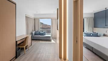 Quarto de hotel moderno com cama, escrivaninha, sofá e vista para o exterior.