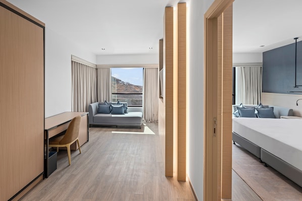 Quarto de hotel moderno com cama, escrivaninha, sofá e vista para o exterior.