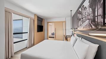 A hotel room with a large bed, a flat-screen TV, a desk with a chair, a window with curtains, and a painting on the wall.