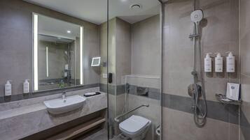 Een moderne badkamer met een douchecabine van glas, een wastafel en een toilet.