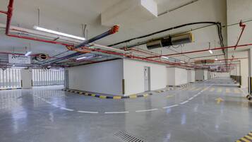 A parking garage with clear directional arrows on the floor, a sign indicating Radisson parking, and various pipes and ducts on the ceiling.