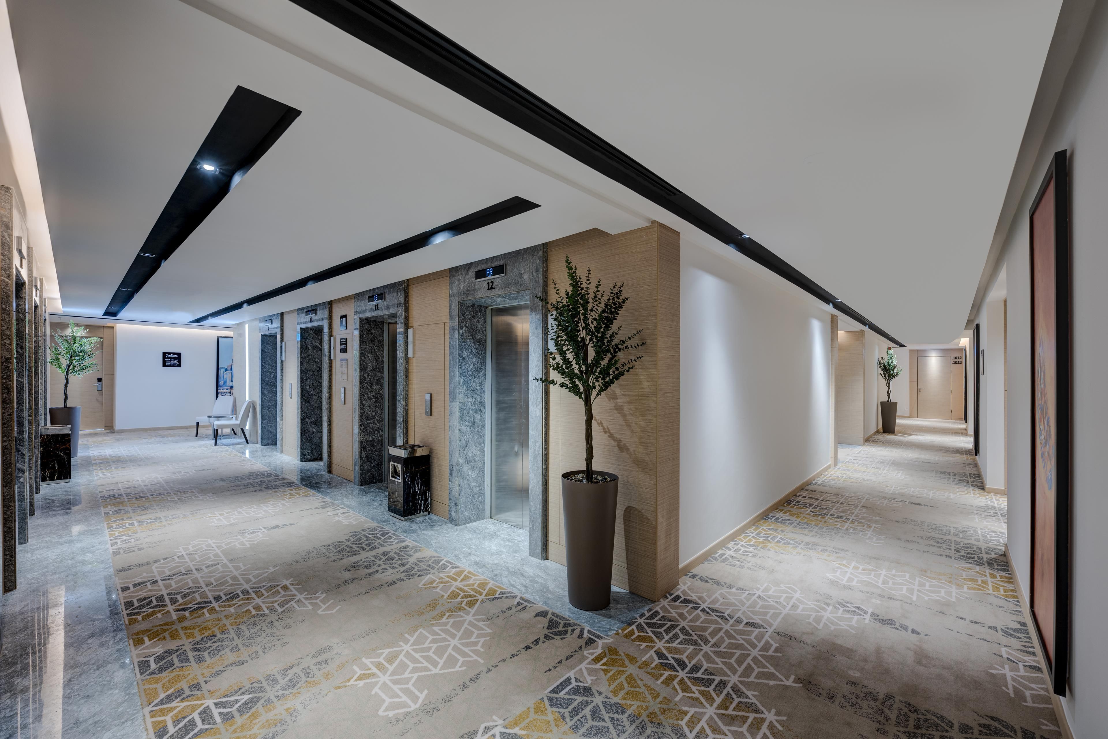 Um lobby de hotel moderno com um piso estampado em padrão geométrico, um balcão de recepção e uma planta em vaso.