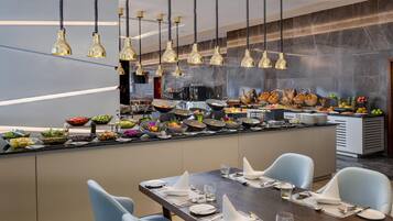 Un restaurante moderno con una barra alargada, varias luces colgantes y una amplia variedad de comida y bebidas.