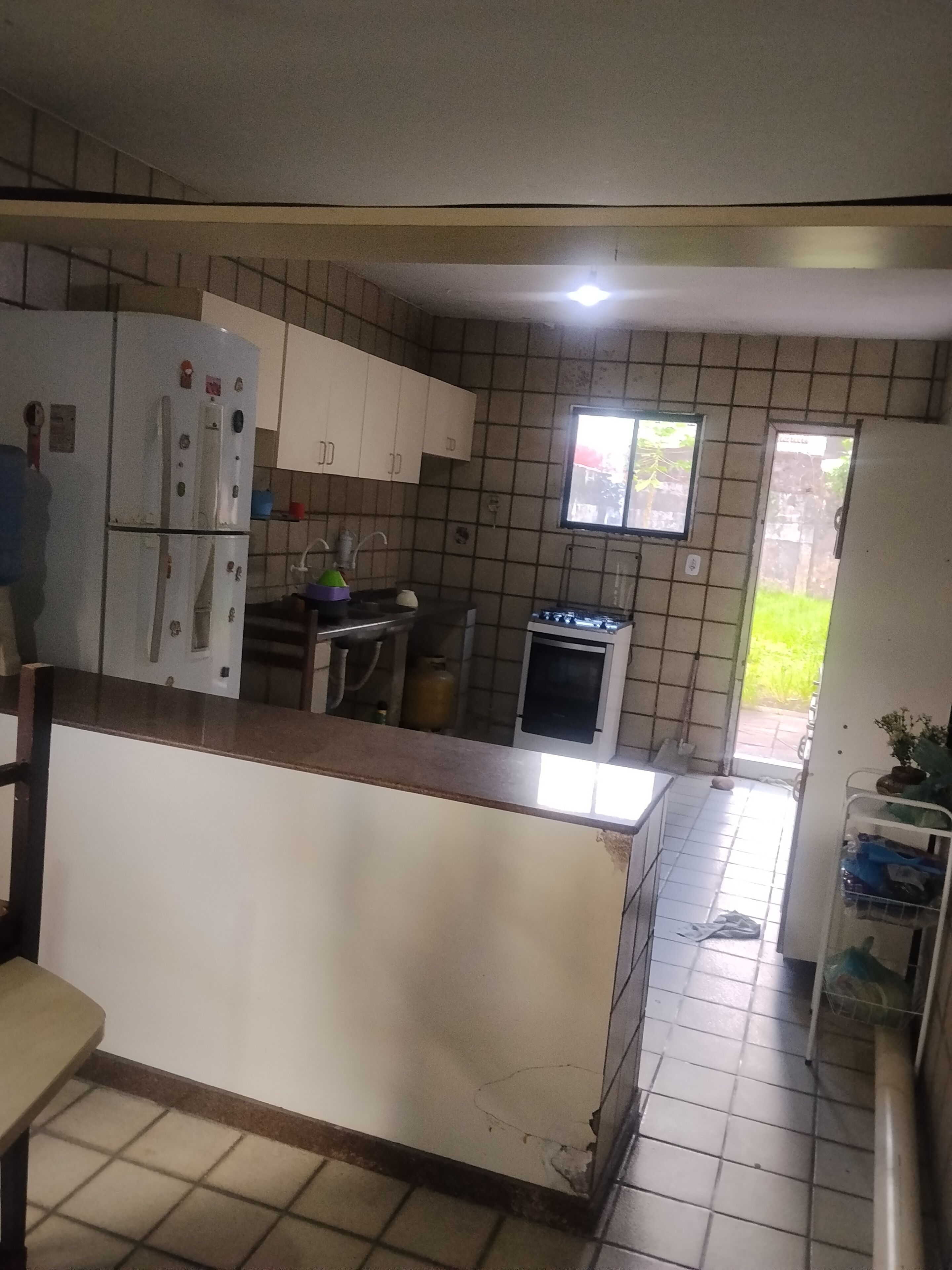 A kitchen with white cabinets, a refrigerator, a stove, and a window.