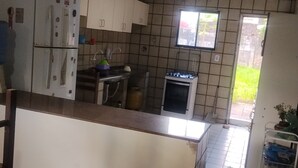 Eine Küche mit weißen Schränken, einem Kühlschrank, einem Herd und einem Fenster.