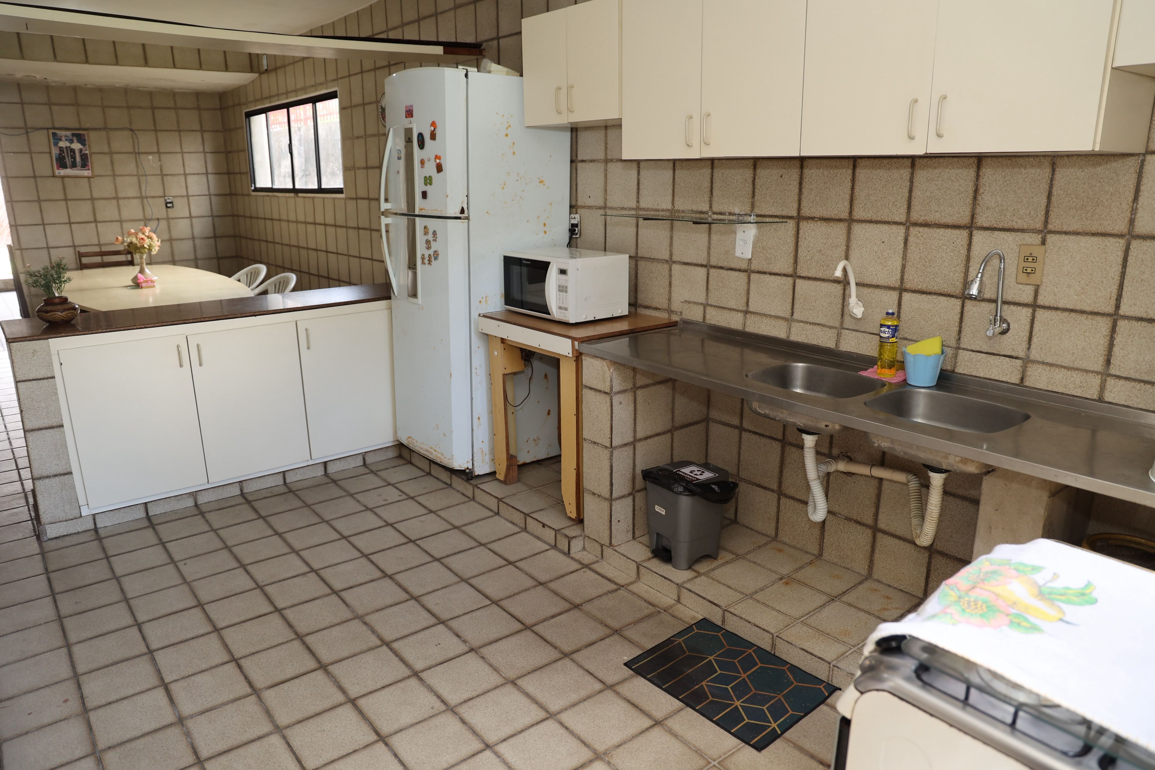 Cozinha compacta com geladeira, micro-ondas, pia e uma pequena lixeira.
