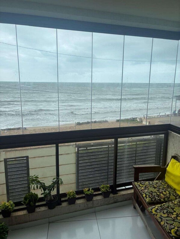 A balcony with a view of the sea, potted plants, and a bed with a patterned bedspread. - Cozy apartment facing the sea in Janga with an incredible view. He comes! (Paulista)
