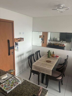 A dining area with a table, chairs, and a kitchen area visible through a mirror. - Cozy apartment facing the sea in Janga with an incredible view. He comes! (Paulista)