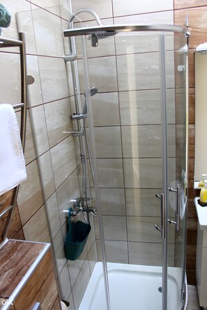 A glass-enclosed shower stall with a white bathtub, a towel rack, and a soap dispenser. - Sarajevo "La Vue" Apartments (Sarajevo)