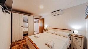 A bedroom with a bed, nightstands, a wardrobe, and an air conditioning unit. - Villa Rosalia Poljice by Villas Guide (Gruda)