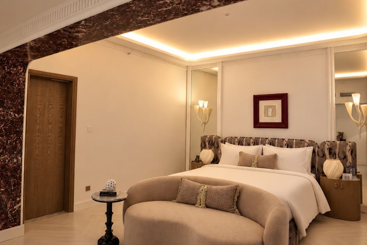 A spacious bedroom with a curved sofa, a large bed, and a mirror.