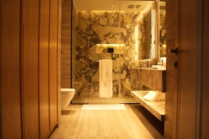 A modern bathroom with a marble wall, a glass shower enclosure, and a wooden floor. - Nishat Hotel Margala (Islamabad)