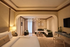 A hotel room with a bed, a sofa, a small table with a fruit bowl, a desk with a chair, and a TV on the wall. - Nishat Hotel Margala (Islamabad)