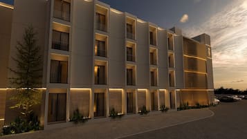 A modern hotel with multiple floors, balconies, and a well-lit facade.