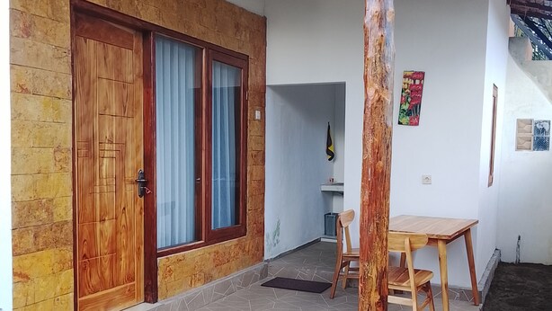 Un patio techado con puerta de madera, una mesa y una silla.