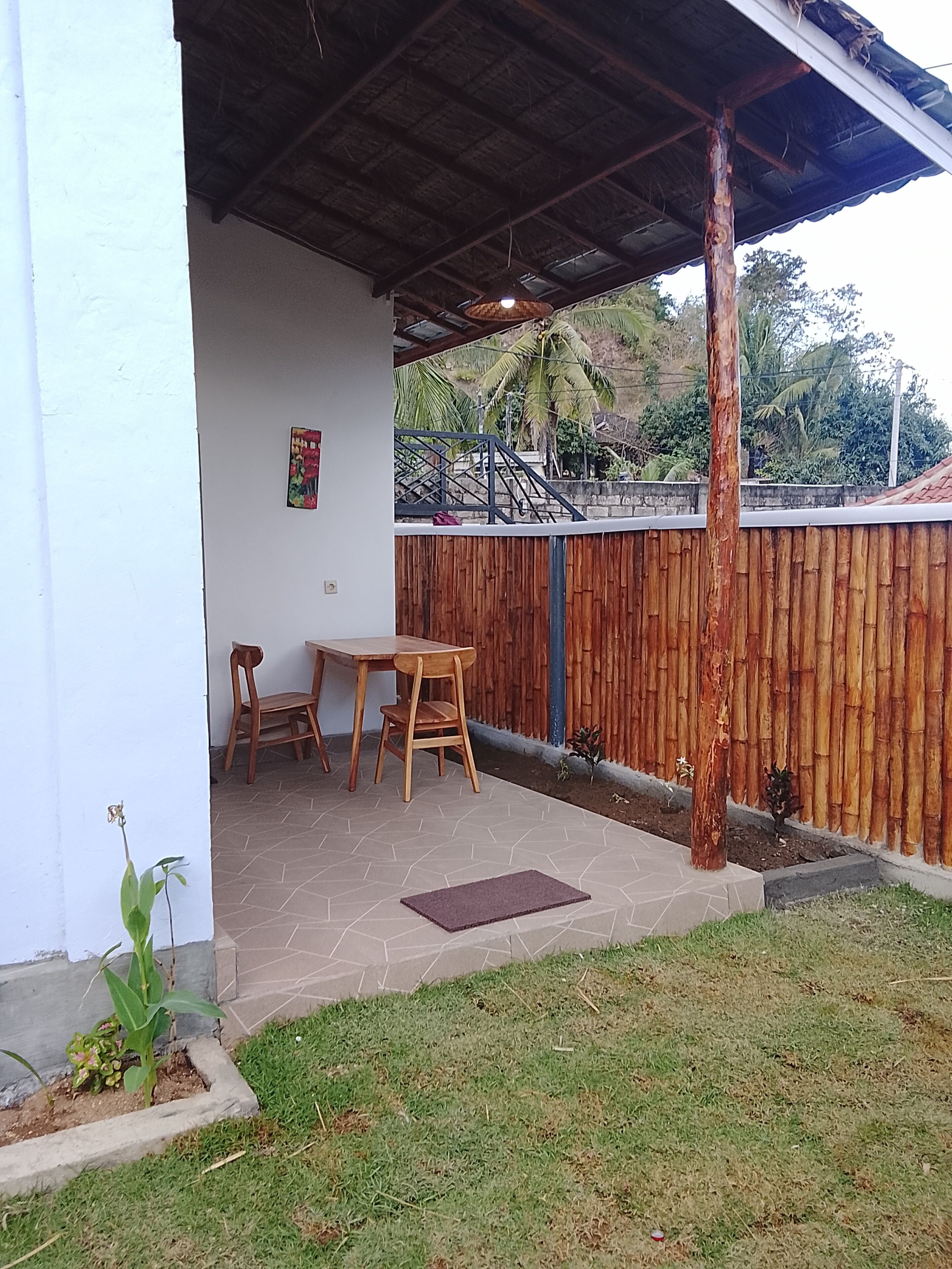 Un espace extérieur abrité, doté d’une table et de chaises, d’une clôture en bois et d’un petit jardin.