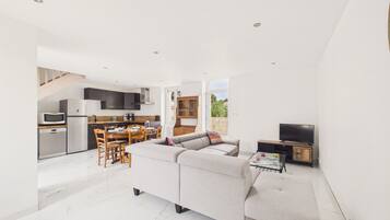 A modern living space with a kitchen, dining area, and a large sofa.