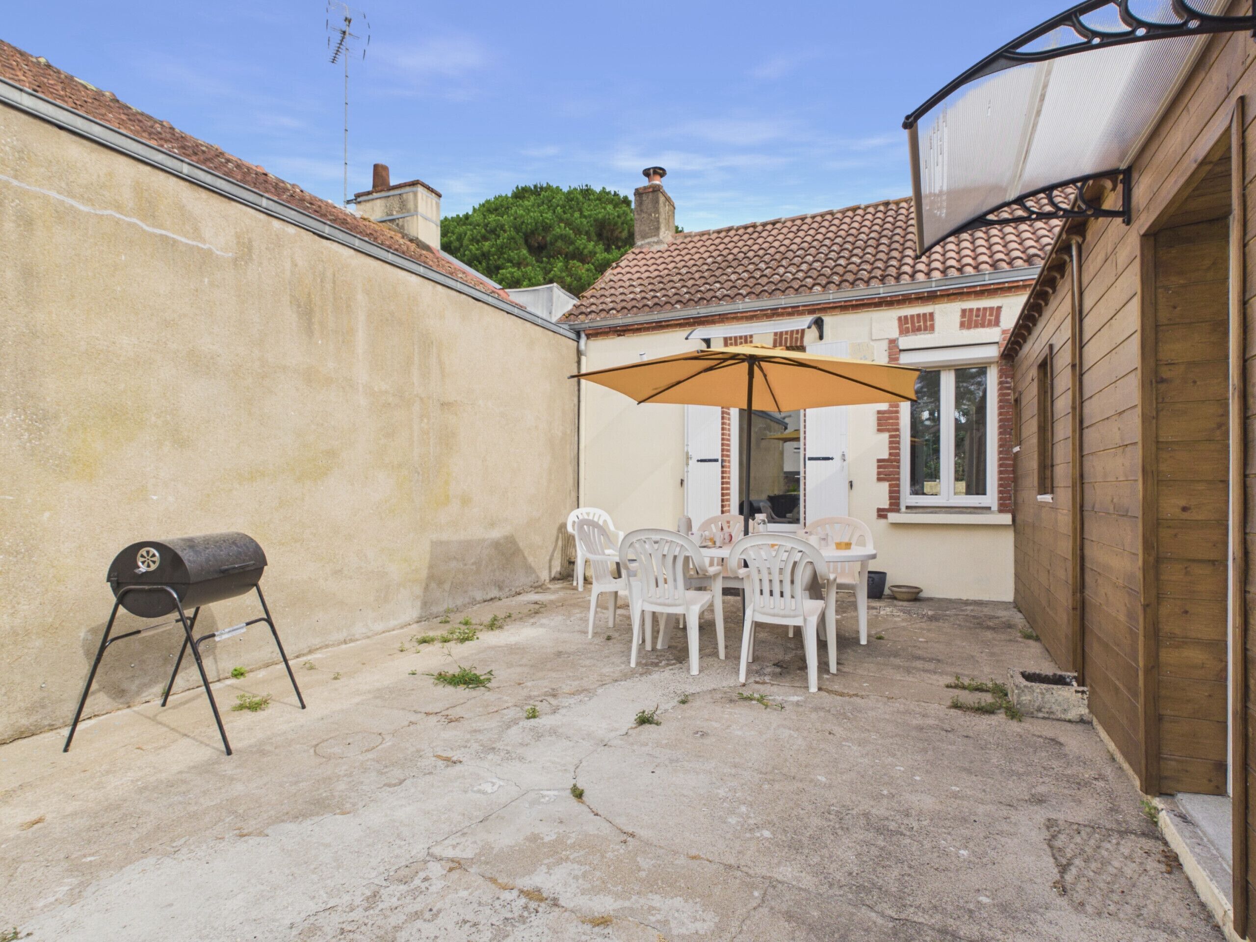 Une terrasse avec un barbecue, une table et des chaises d’extérieur.
