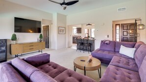 A modern living room with a large flat-screen TV, a ceiling fan, and a purple sofa set. - 2 Mi to Lake Havasu! Mtn-view Poolside Paradise (Lake Havasu City)