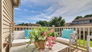 Une terrasse dotée de mobilier d’extérieur, agrémentée d’un arrangement floral et offrant une vue sur les maisons voisines.